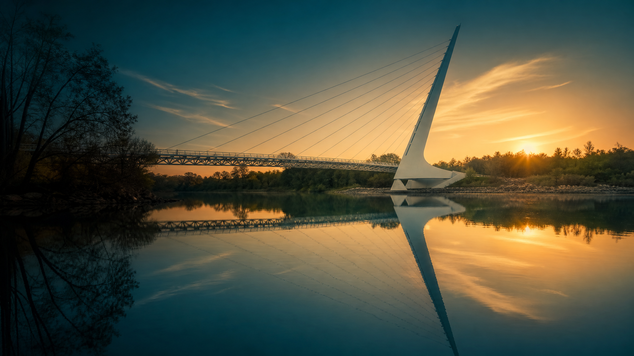 The iconic Sundial Bridge in Redding, California reflected in the calm Sacramento River at golden-hour sunset